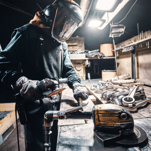 Man in uniform and protective mask is working at metal factory.