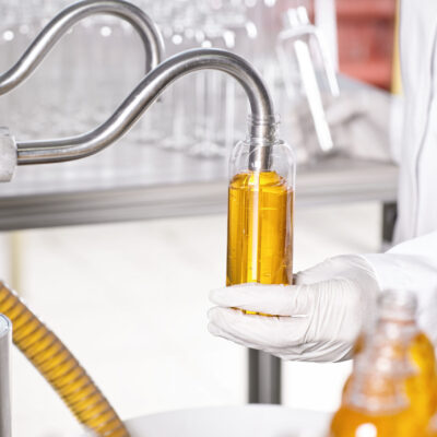 Large scale production of cosmetic in factory.Chain of production of new kind of cream by researcher. Interior of modern laboratory. A researcher in white medical gown holding glassware in hands